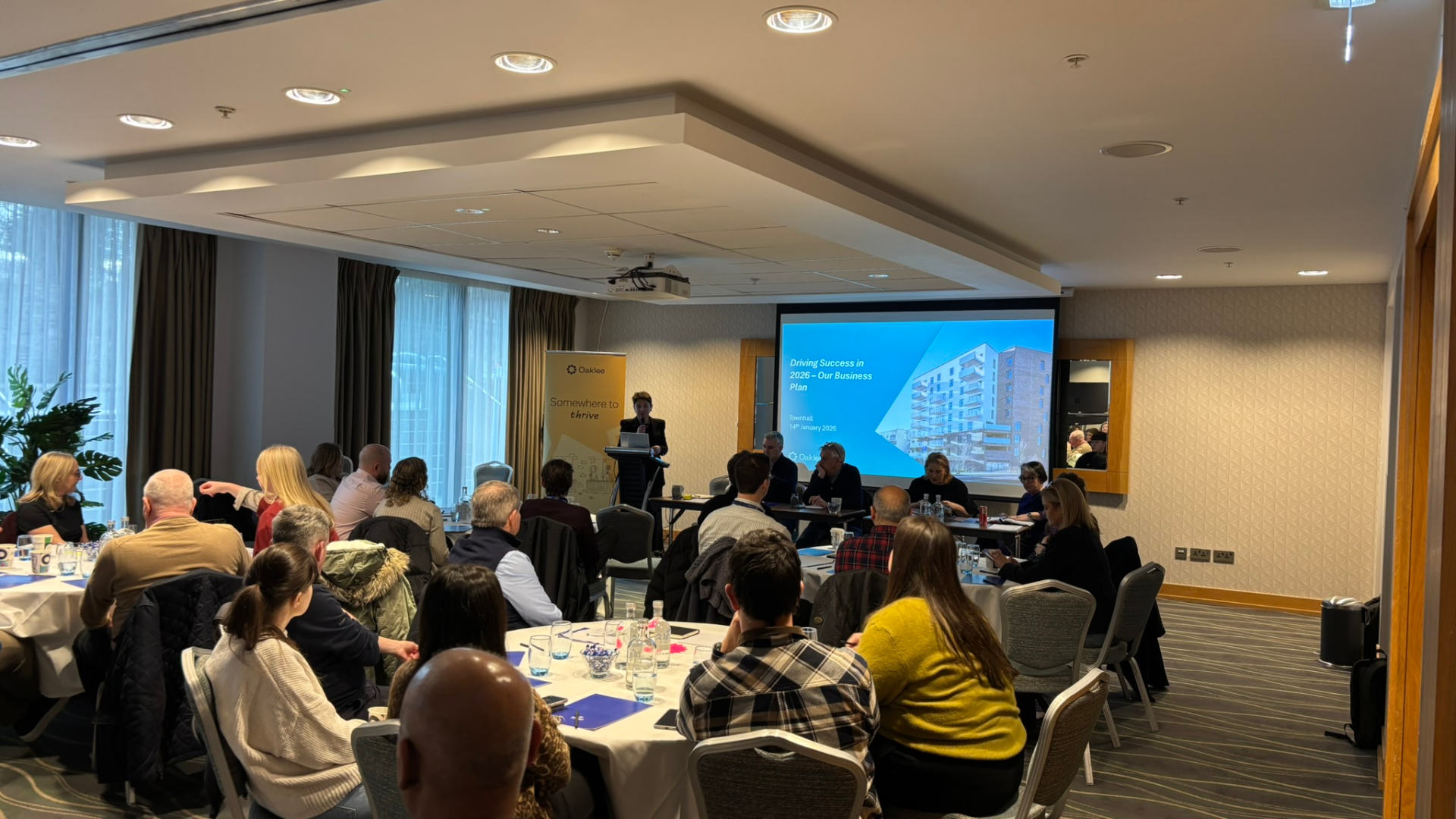 Attendees watching a presentation titled “Driving Success in 2026 – Our Business Plan” during the Town Hall event.